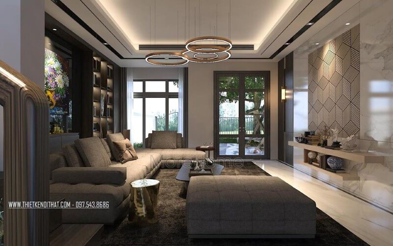 Phòng khách hiện đại sắc trầm nhưng rộng rãi, thông thoáng với cửa sổ, cửa chính kính lớn. Thiết kế nội thất phòng khách biệt thự